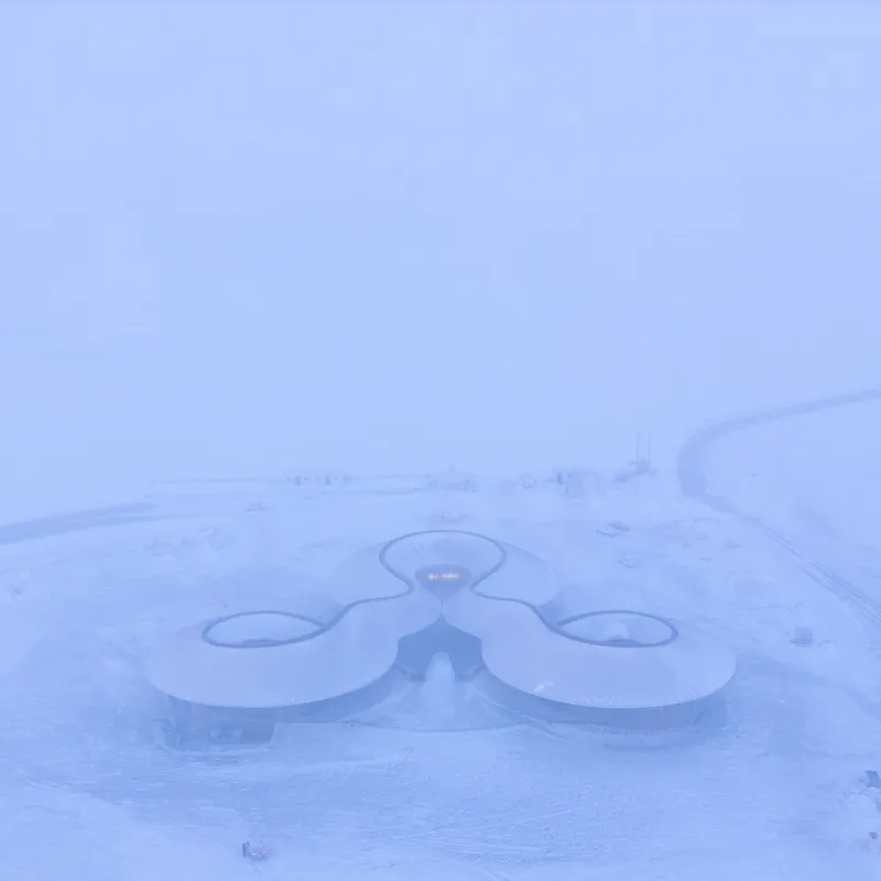 Top-down view of the three-lobed roof in heavy snow and mist