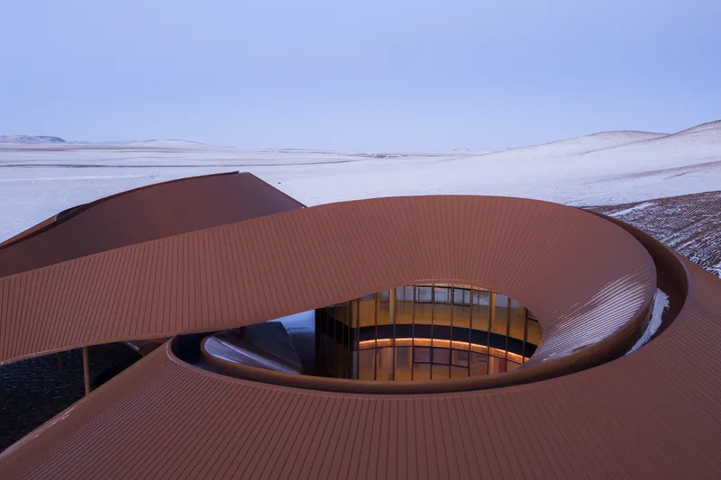 Detail of the curving roof and one of the circular skylight openings glowing yellow