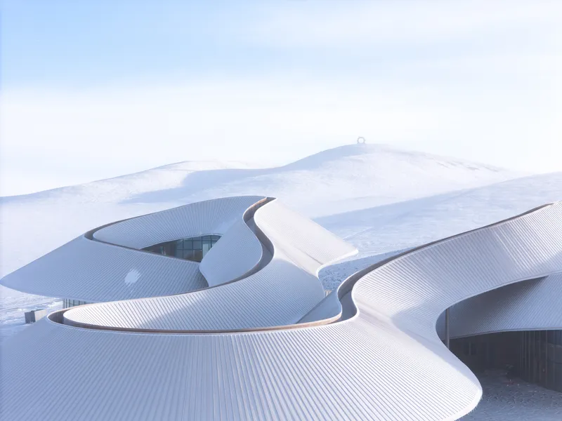 Snow blanketing the ribbed roof so it almost merges with the surrounding hill