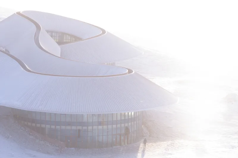 Front view through mist showing the glazed ground floor under the curving roof