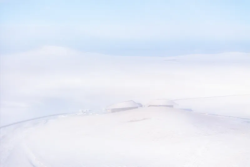 Almost-monochrome view of the building barely visible in the snowfield
