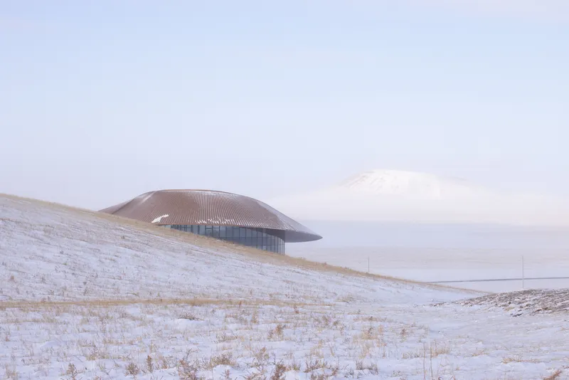 View across the steppe with the building on a low ridge and the volcano cone in the distance