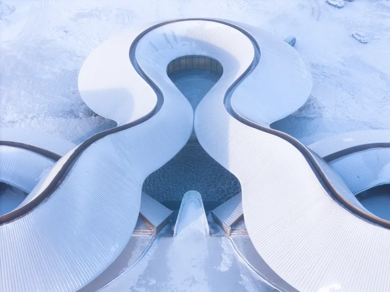 Top-down view of the snow-covered roof showing its symmetrical curving plan