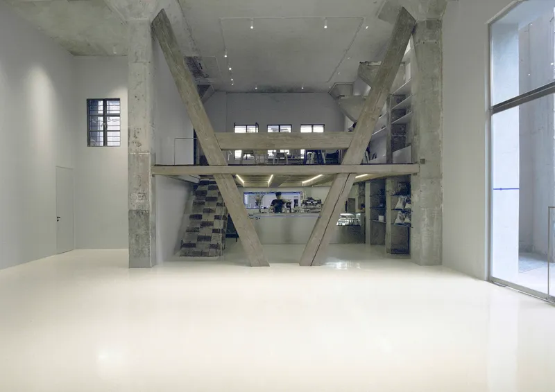 Full-height view of diagonal concrete bracing supporting three stacked mezzanine floors with open workspaces