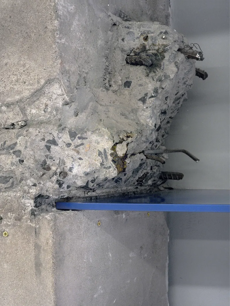 Close-up detail of deteriorated concrete with exposed aggregate and embedded metal reinforcement bars