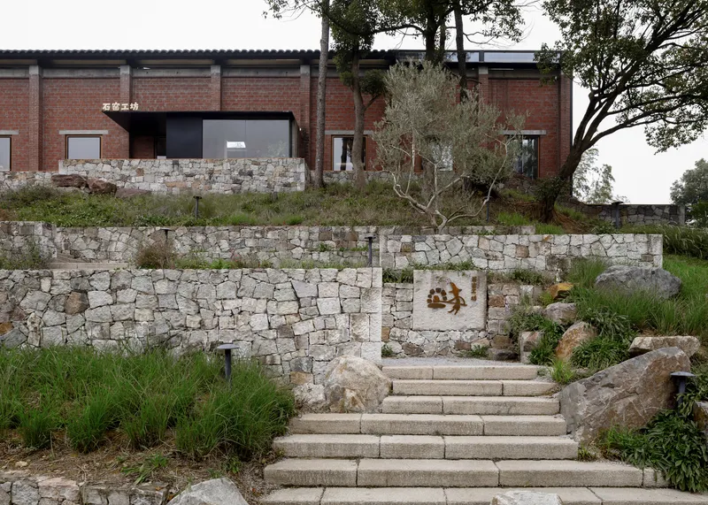 Stone stairs ascending through terraced dry-stone retaining walls with grasses and trees