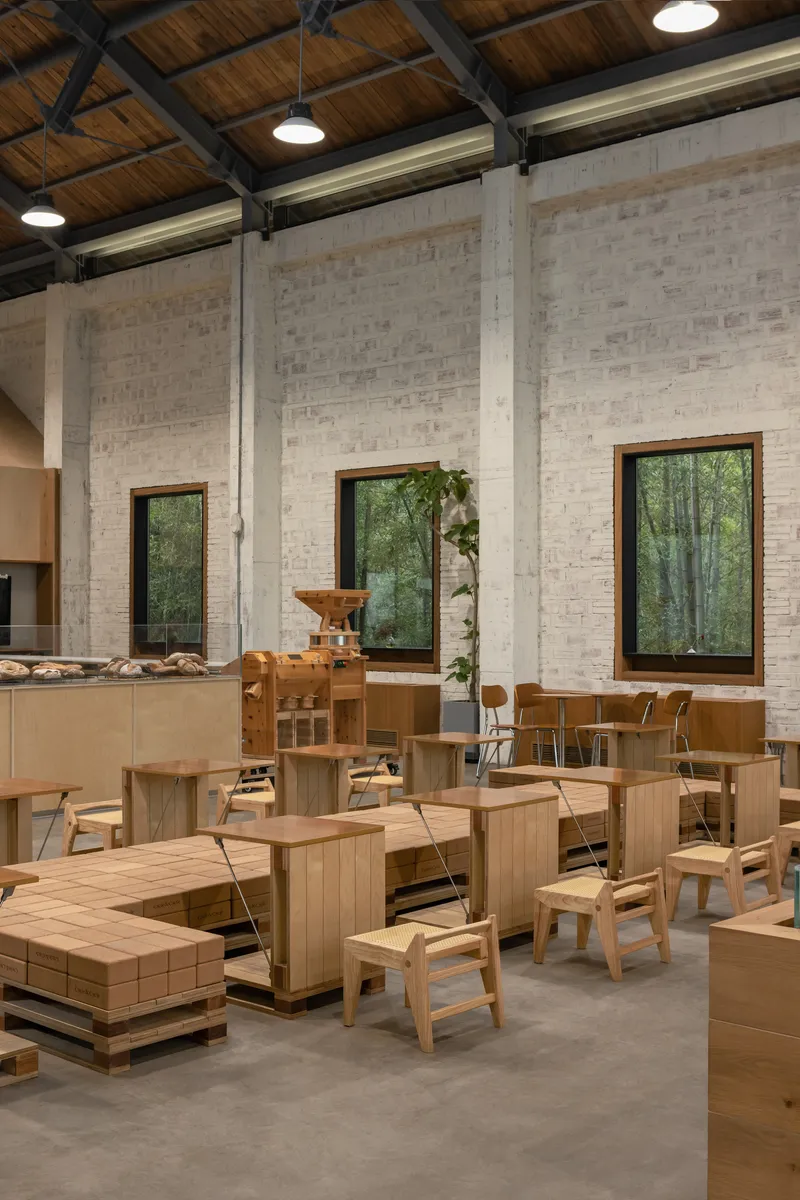 Interior dining space with whitewashed brick walls, timber ceiling with exposed steel trusses and pendant lights