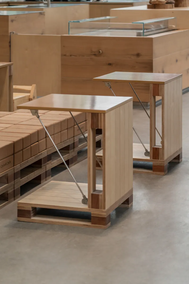 Pair of timber display plinths with steel cable bracing and glass tops on concrete floor