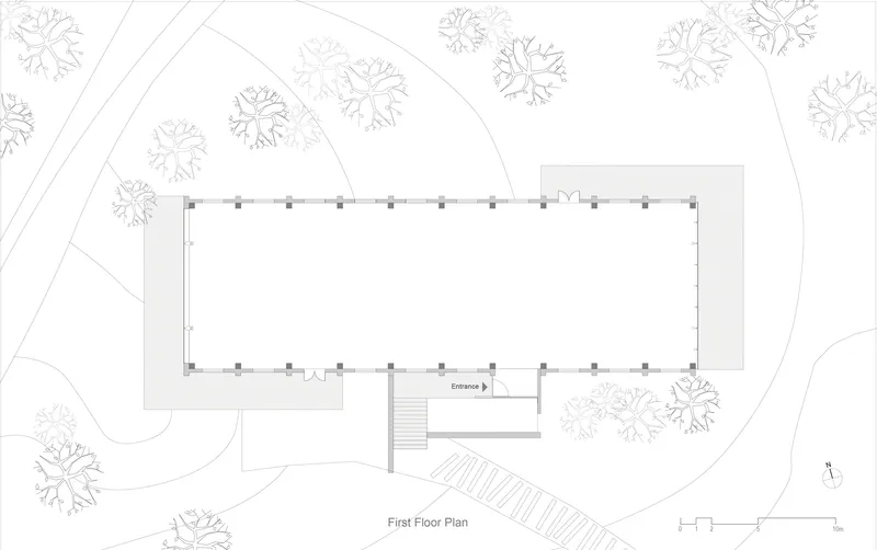 Site plan drawing showing a rectangular building footprint surrounded by trees with a stepped entrance approach