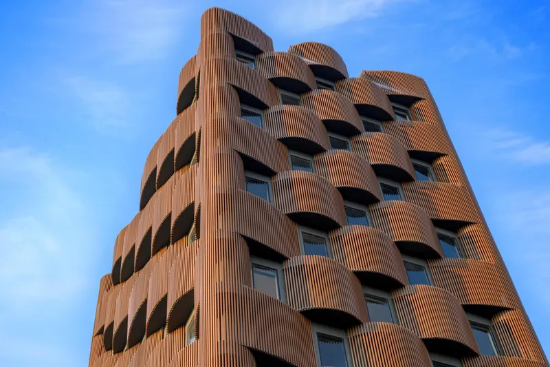Full elevation showing the tapered tower with terracotta louvers and rhythmic pattern of recessed balconies