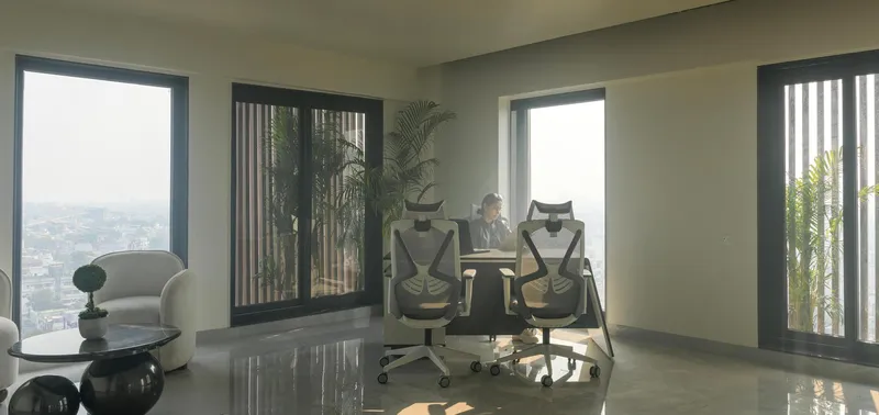 Interior workspace with glass doors opening to terracotta-screened balconies overlooking the cityscape
