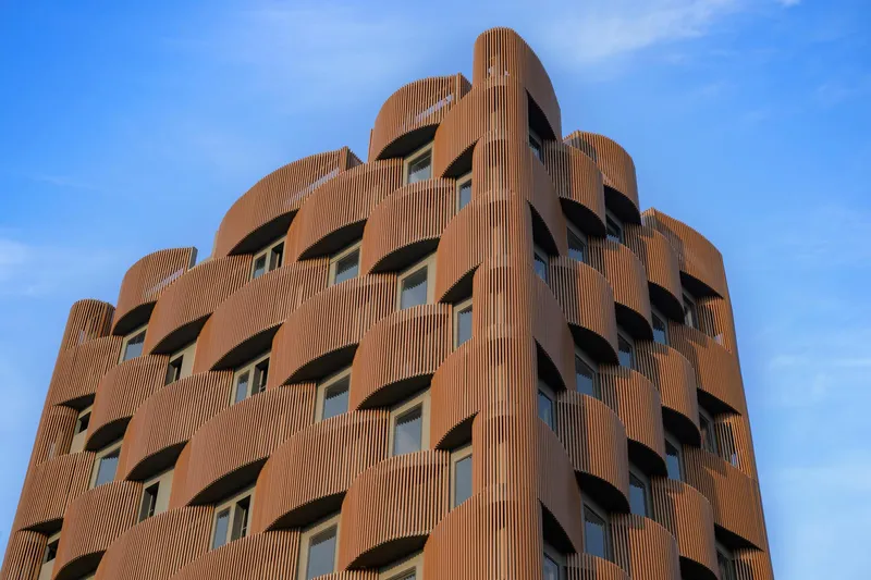 Close-up of the sculptural terracotta louver facade with recessed balconies against a clear sky