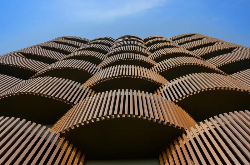 Upward view of the curved terracotta fins forming repeating arched patterns across the tower facade