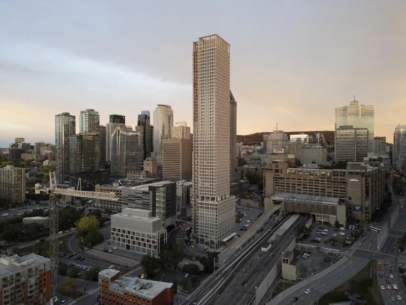 Aerial view of the tall residential tower rising above the urban fabric at dusk