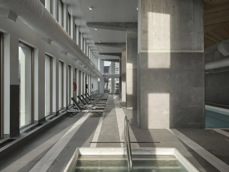 Pool deck with concrete columns casting rectangular shadows from tall windows along the perimeter