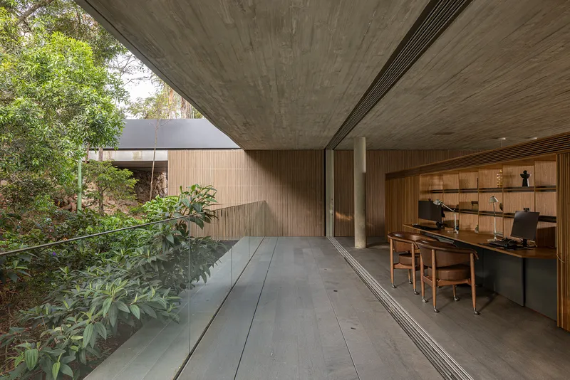 Covered terrace with concrete ceiling opening to planted courtyard and timber-clad study beyond
