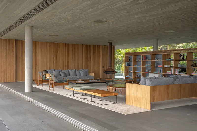 Covered living area with timber walls, white columns and open shelving overlooking the garden