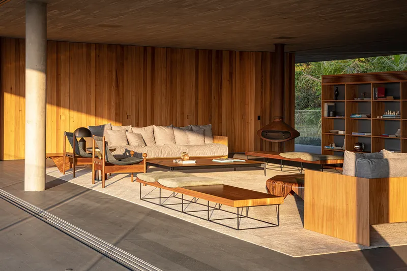 Covered lounge with freestanding fireplace and vertical timber cladding in golden afternoon sun