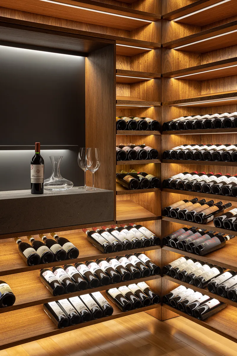 Wine cellar with timber shelving, integrated LED lighting and grey display counter with glassware