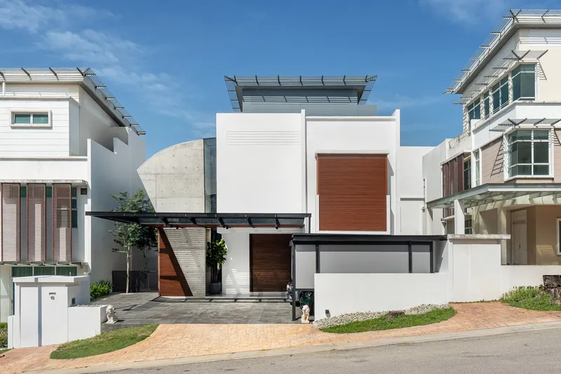 Street view of white stucco volumes with timber panels and a cantilevered canopy under a blue sky