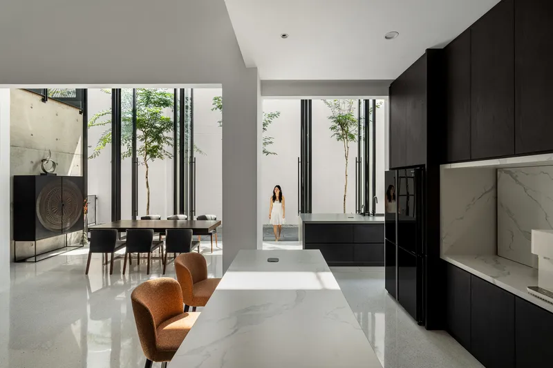 Open living and kitchen space with polished terrazzo floor and views to two planted courtyards