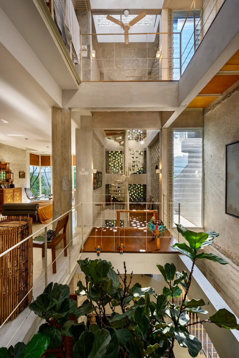 Triple-height atrium with concrete columns, exposed timber beams and planted courtyard below glass bridges