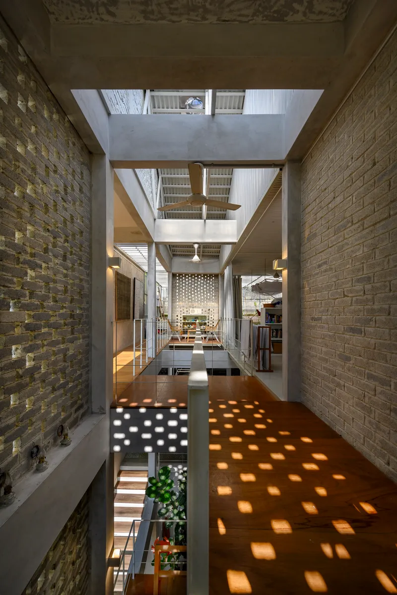 Upper level walkway with perforated screen wall casting dappled sunlight onto the polished concrete floor