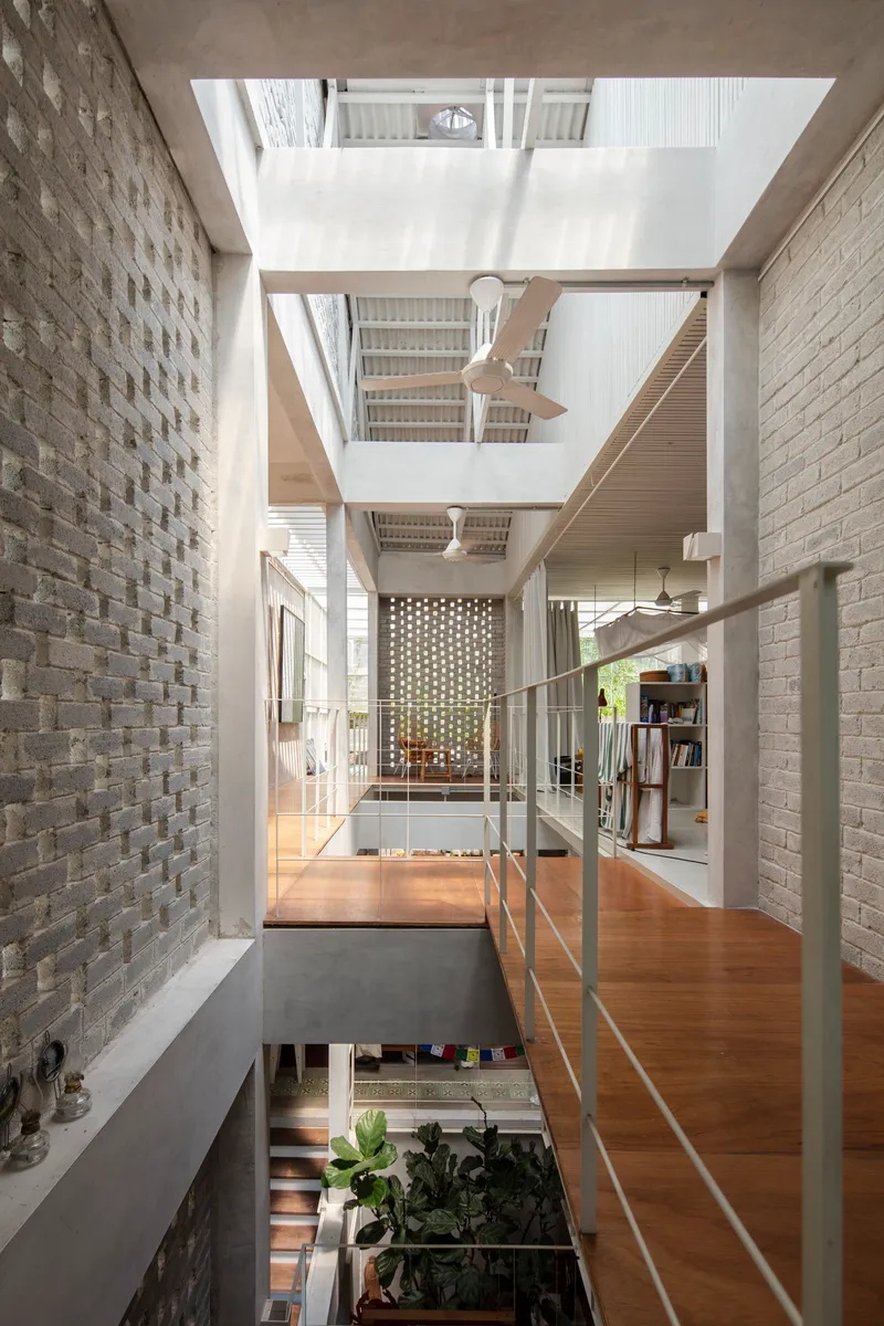 View through glass-railed bridge showing stacked levels and central void under a large skylight