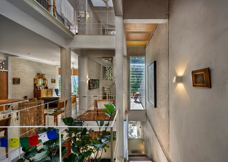 Multi-level interior with exposed concrete columns and mezzanines connected by stairs and planted areas below