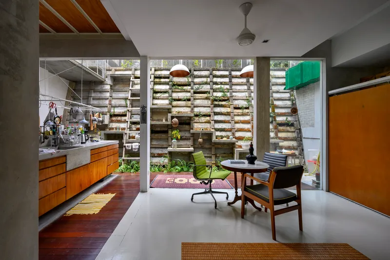 Living space opening to internal courtyard through concrete frame with horizontal louvered planting wall beyond