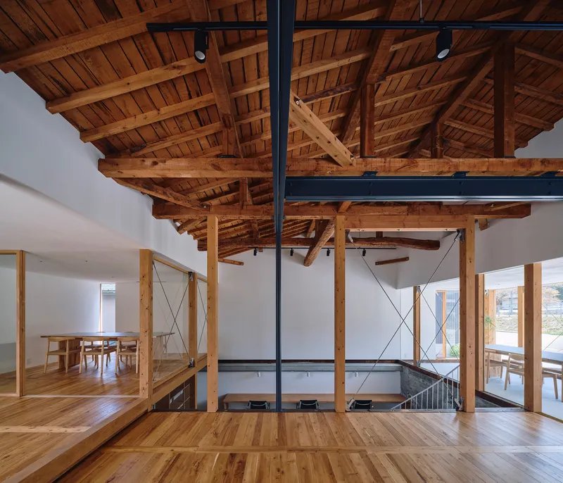 Exposed timber ceiling with beams and planking above a split-level space with steel guardrails