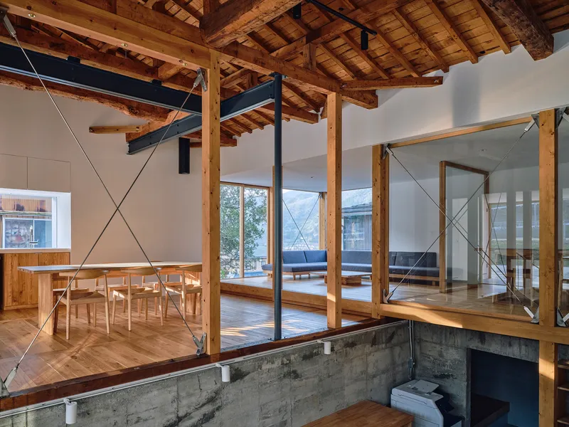 Split-level interior showing exposed timber ceiling structure and concrete base with dining area above