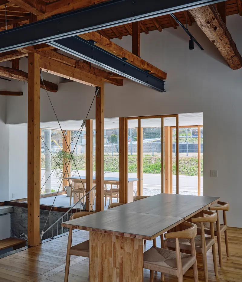 Dining space with exposed timber posts and steel beam beneath pitched wood ceiling and cable bracing