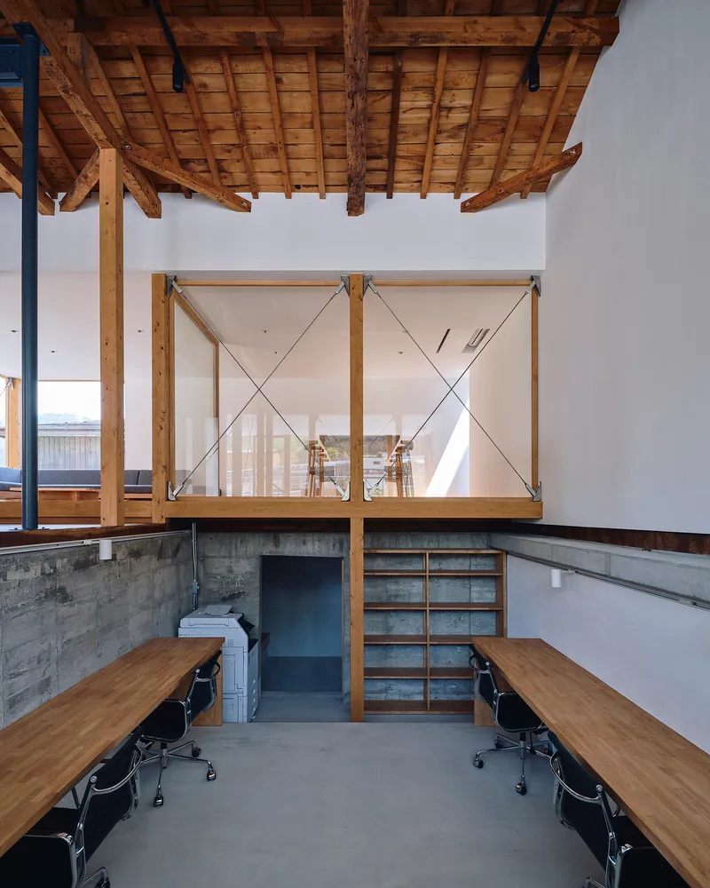 Interior workspace with timber frame partition above poured concrete walls and polished concrete floor