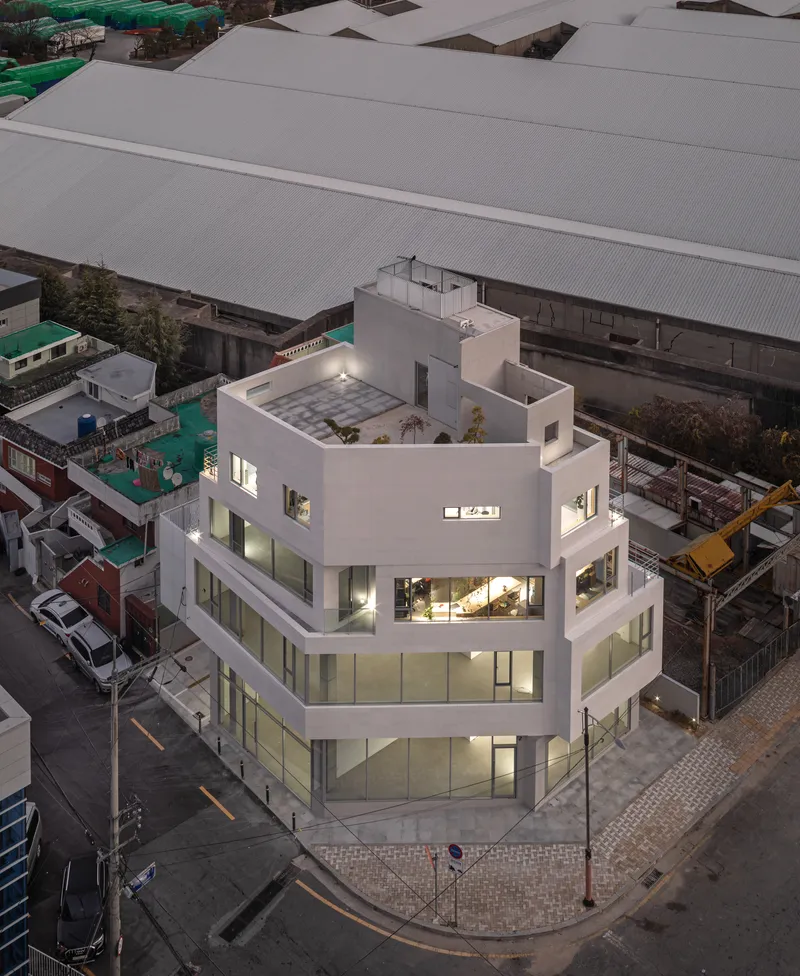 Aerial view of the corner building at dusk showing rooftop terrace and surrounding industrial sheds