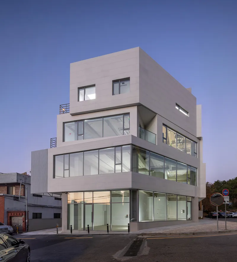 Street corner facade with offset floor plates and illuminated interiors at twilight