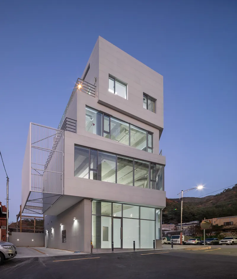 Side elevation showing metal screen stairwell and cantilevered volumes in evening light