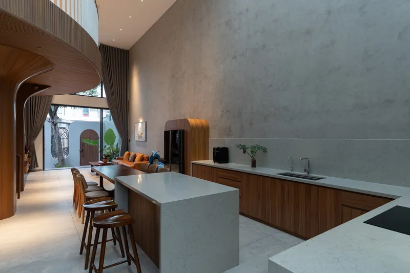 Open kitchen with marble waterfall island looking toward arched windows and planted courtyard at dusk