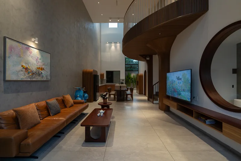 Living room with circular timber portal framing media wall and view to curved mezzanine structure