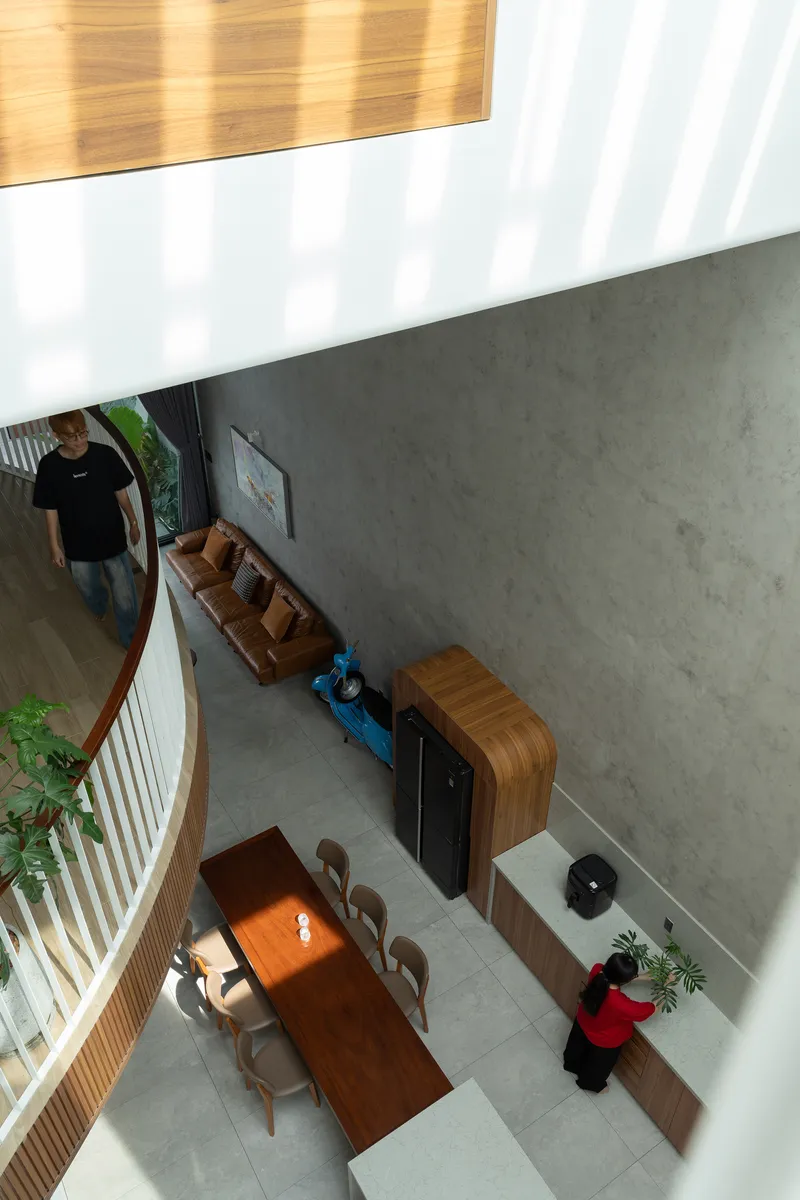 Overhead view of the double-height dining area with concrete walls and striped sunlight filtering through timber screens