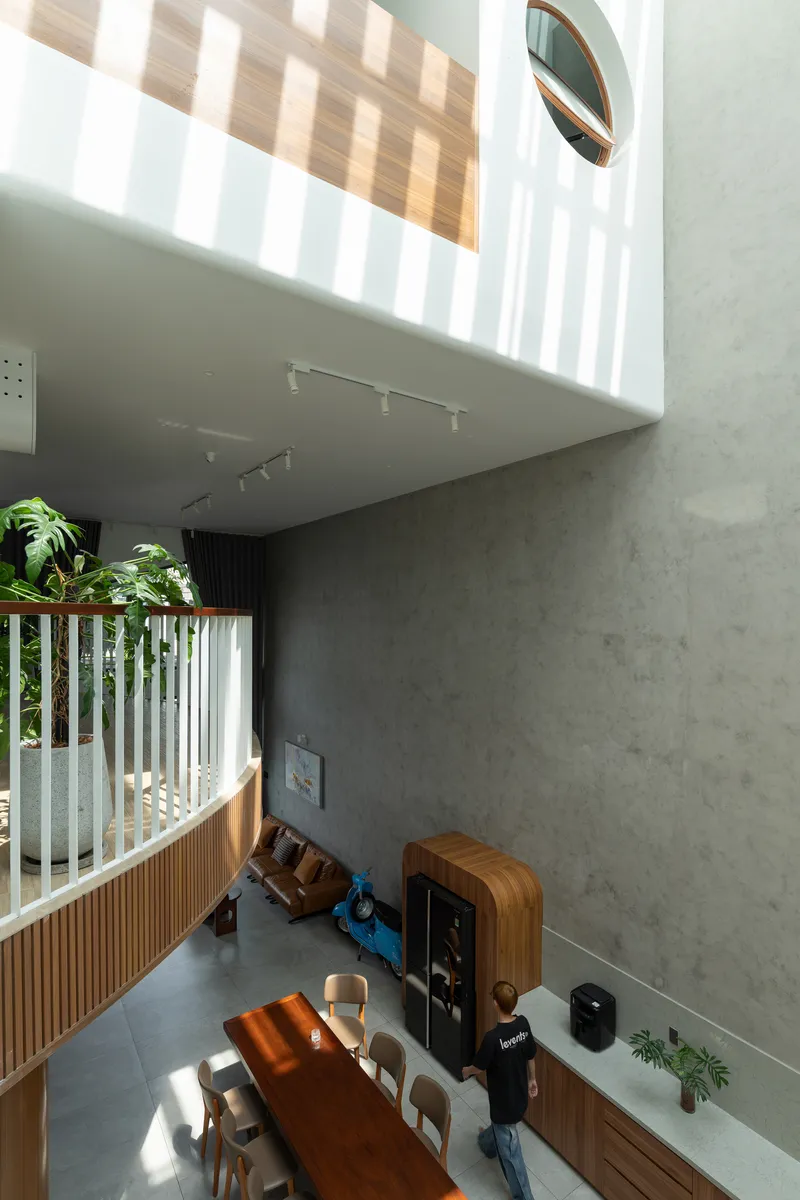 View down into the living area showing timber balustrade, concrete walls, and dappled afternoon light