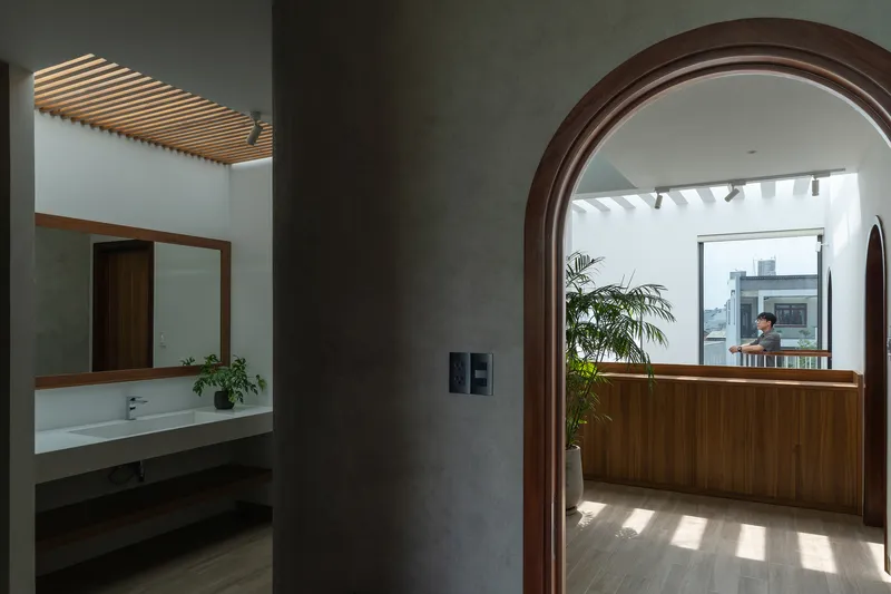 Arched timber doorway framing the wood-paneled kitchen beneath a slatted skylight