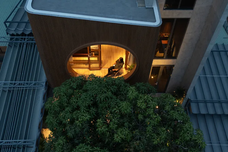 Overhead view of the circular terrace window with a figure seated inside above dense green planting