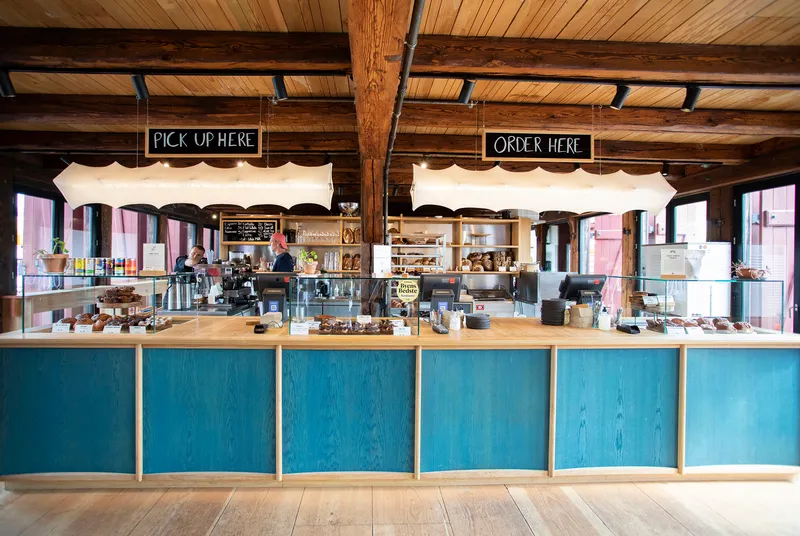Service counter with blue-stained wood panels and timber ceiling beams with exposed steel brackets