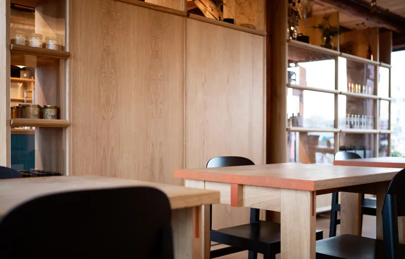 Seating area with light wood table and chairs beside plywood sliding doors and display shelving