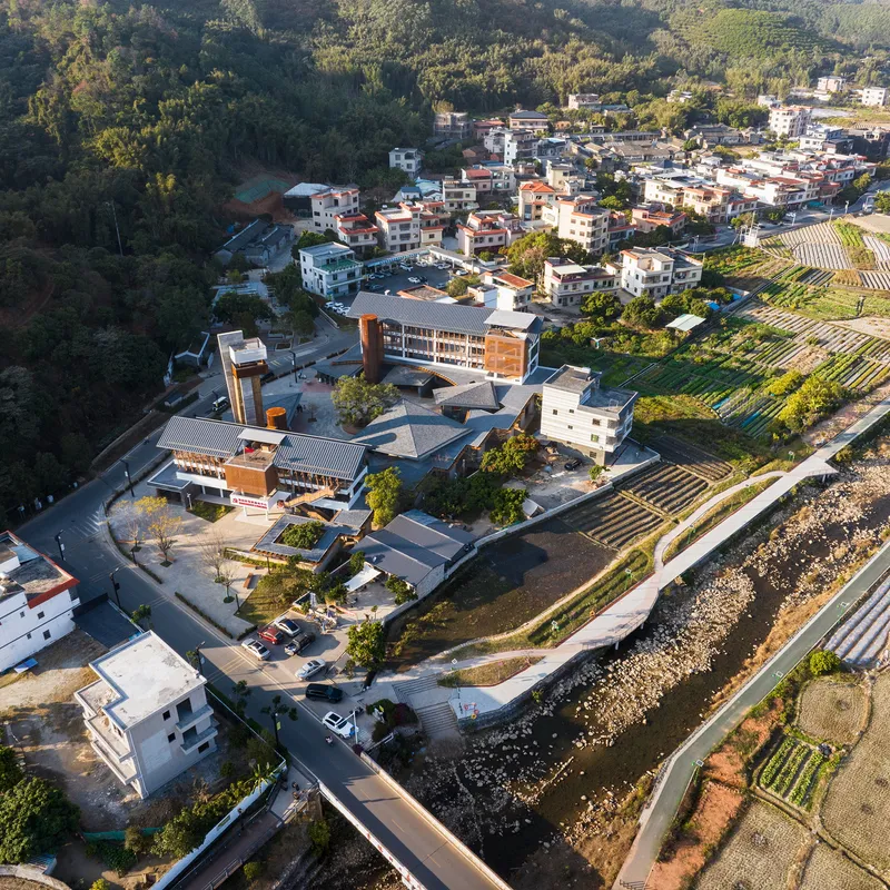 Aerial view of the compound with tower and low roofs nestled between village and agricultural fields