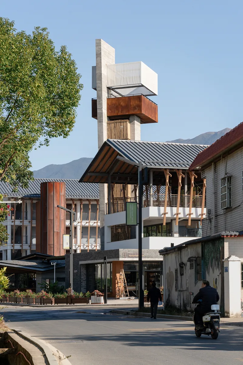 Street view of the concrete tower rising above tiled roofs with a motorcyclist passing
