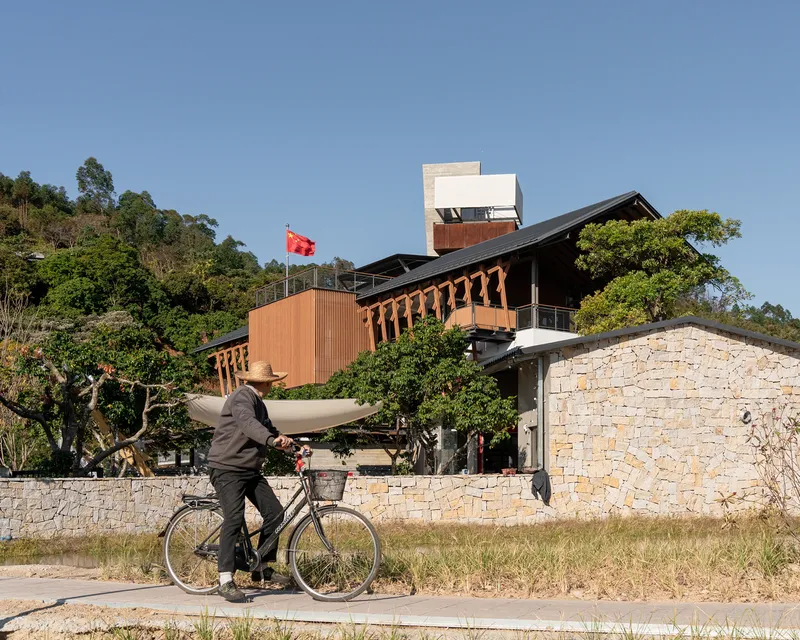 Cyclist passing stone retaining wall with layered rooflines and observation tower beyond
