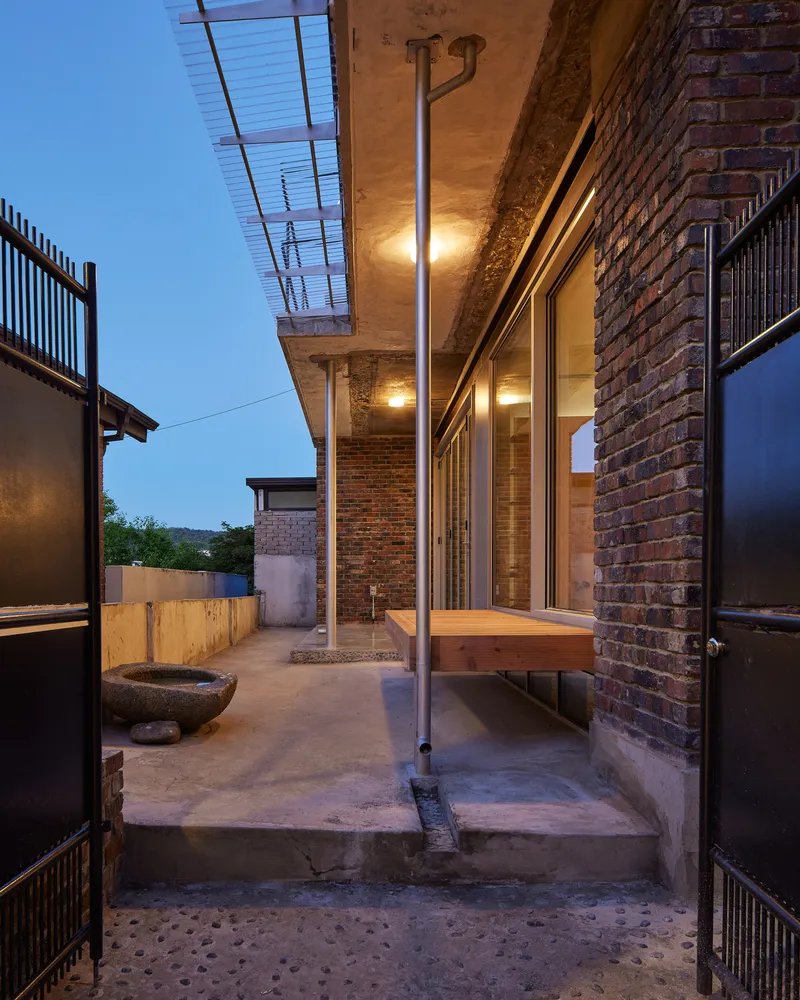 Covered concrete terrace with steel column and brick walls beneath an exposed aggregate ceiling
