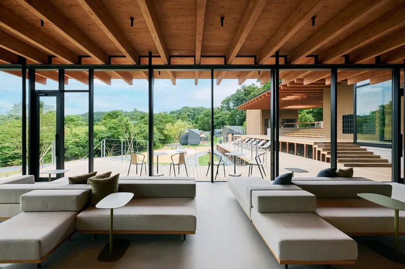 Interior lounge with exposed timber ceiling beams and floor-to-ceiling glass overlooking the terraced grounds